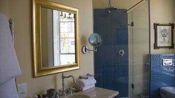 A bathroom with a large mirror, a sink, a shower, and a toilet.
