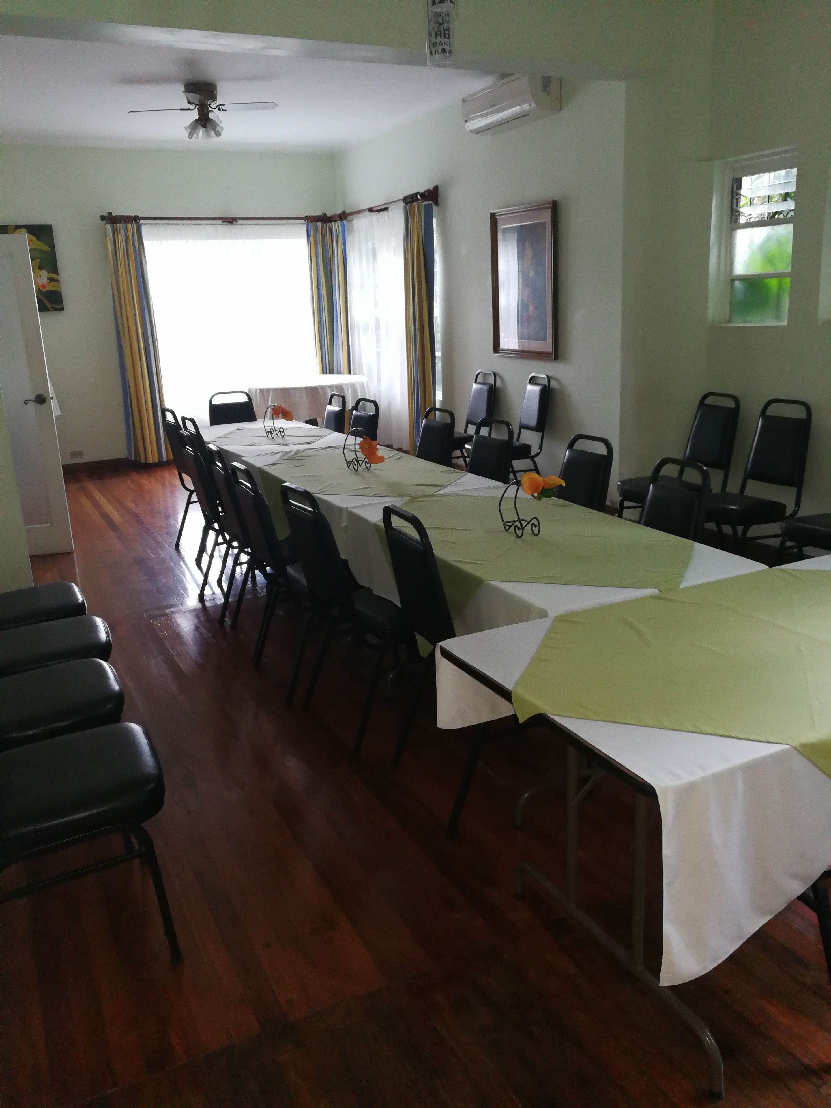 A conference room with a long table, chairs, and a ceiling fan.