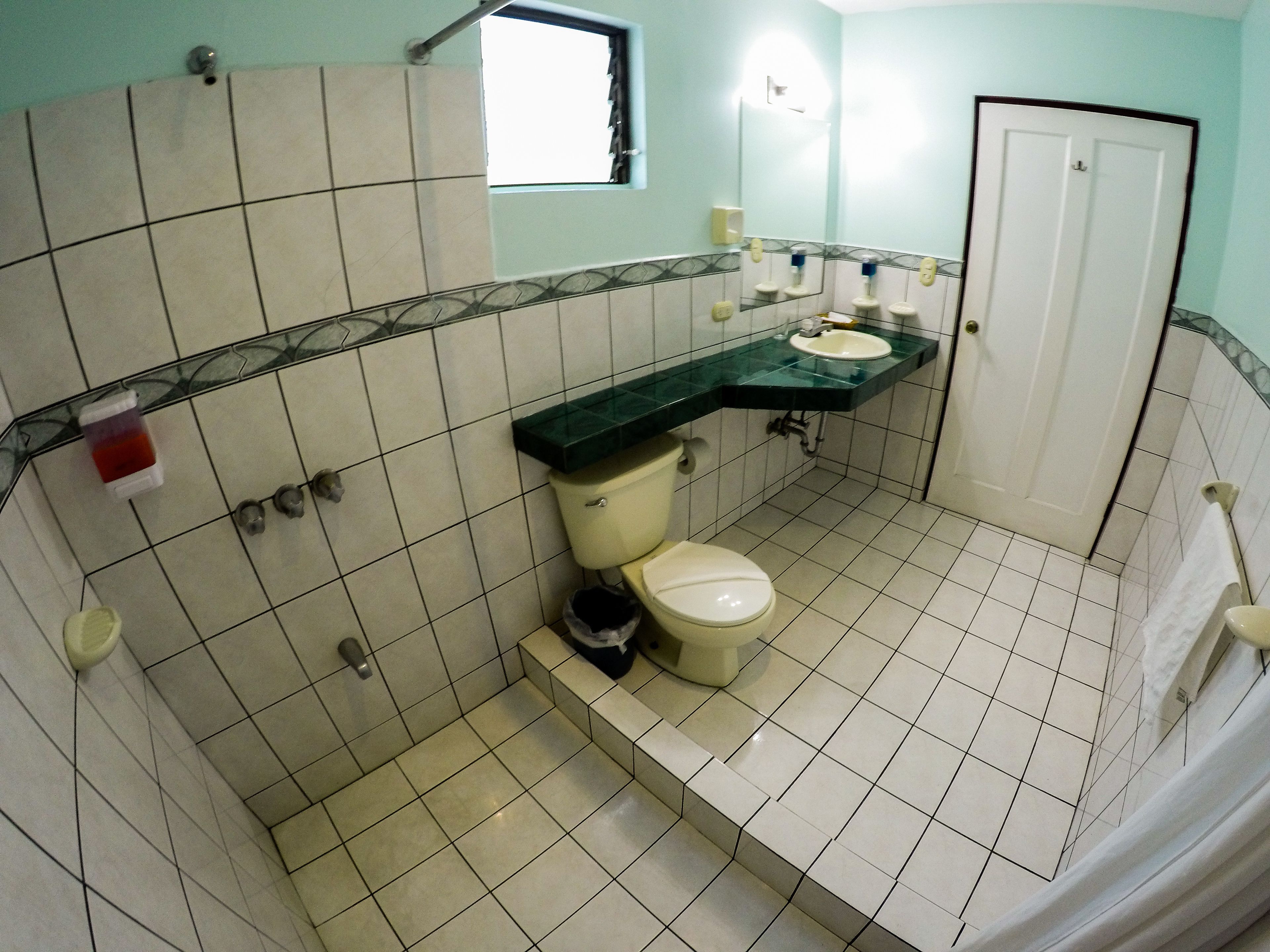 A bathroom with a toilet, sink, and shower area.