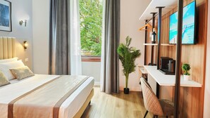 Une chambre d’hôtel moderne, dotée d’un grand lit, d’un bureau, d’une télévision et offrant une vue sur la verdure environnante.