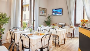 Un espace repas comprenant plusieurs tables, des chaises et un téléviseur fixé au mur.