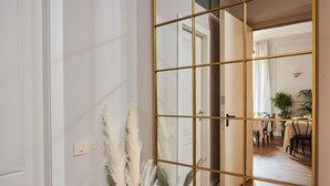 Une pièce avec un mur recouvert de miroirs, une porte et un coin repas comprenant des chaises et une table.