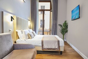 Una habitación de hotel moderna con una cama, un sofá, una planta en maceta y un cuadro en la pared.