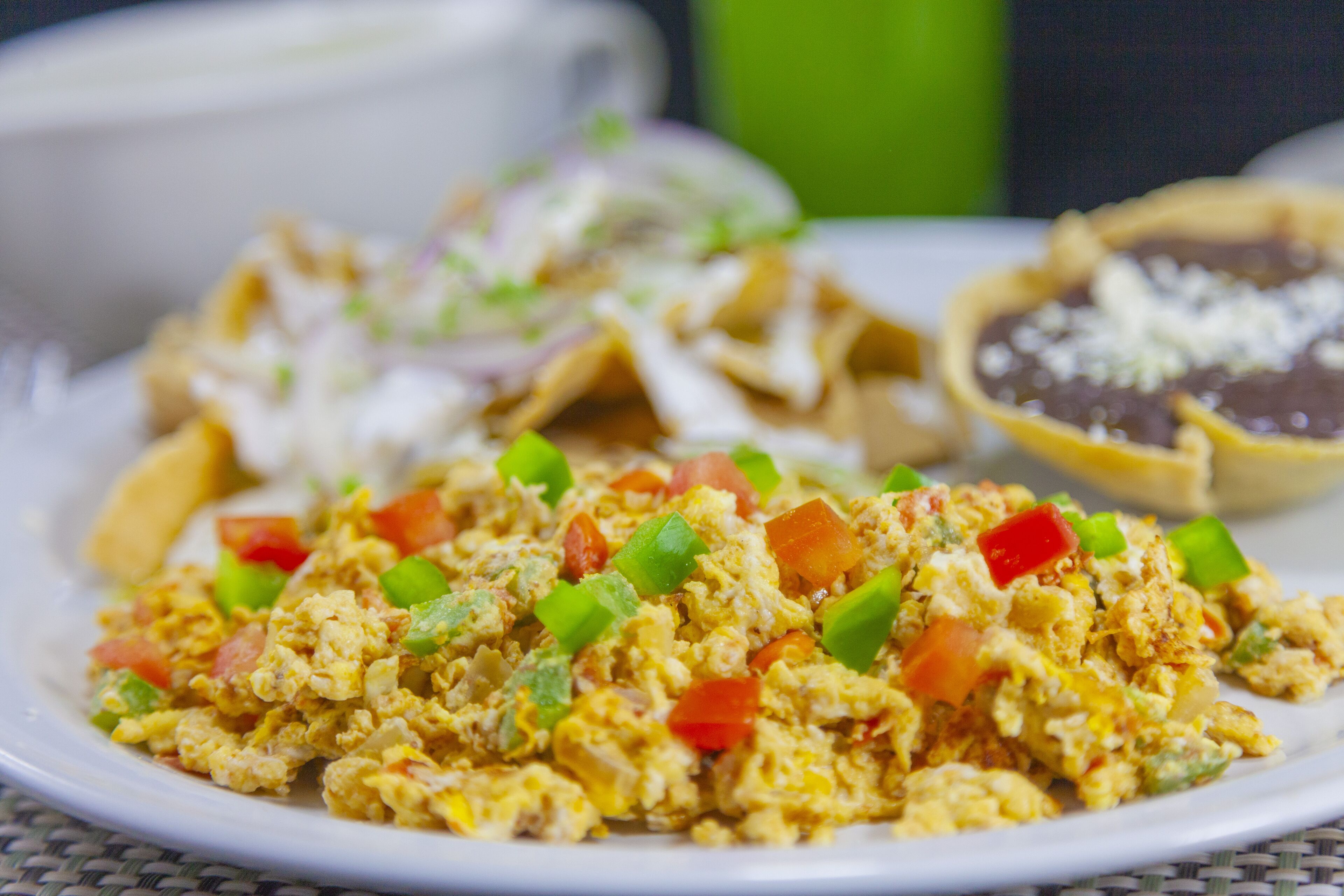 A plate of scrambled eggs with vegetables and a side of refried beans.