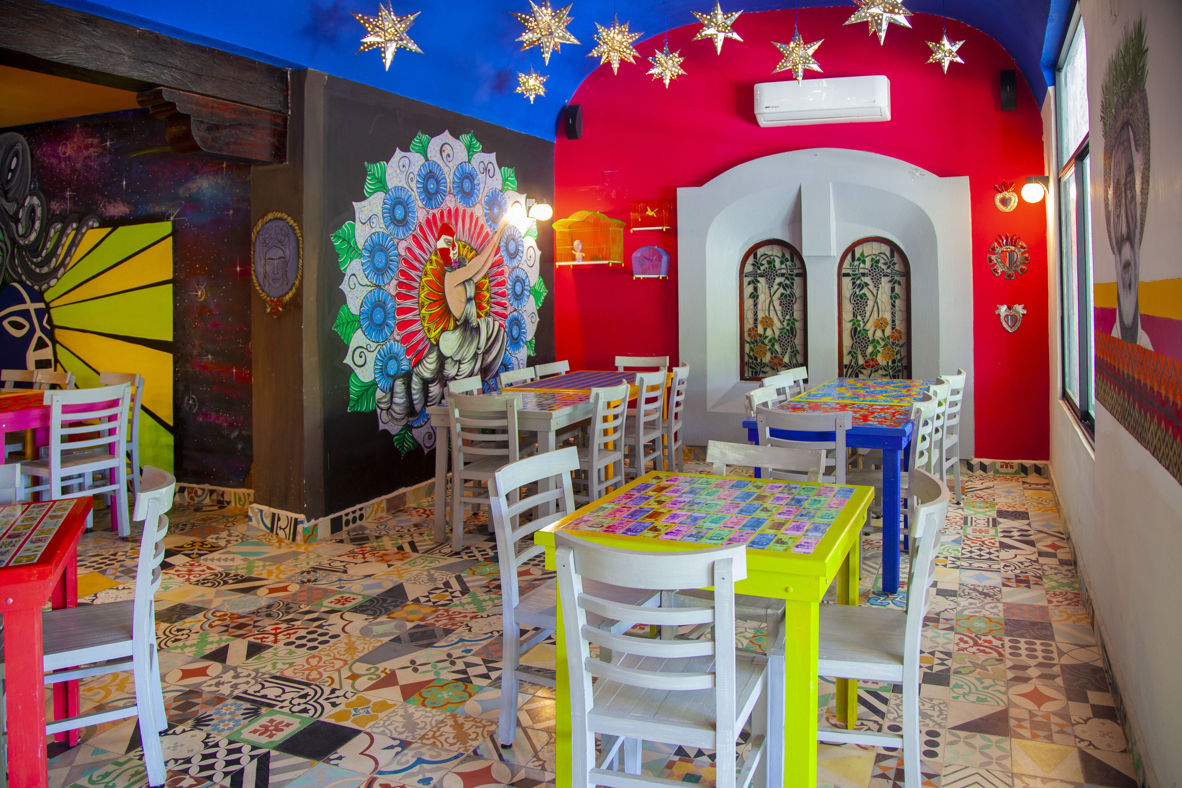 Un interior lleno de color con suelo estampado, mesas y sillas blancas y amarillas.
