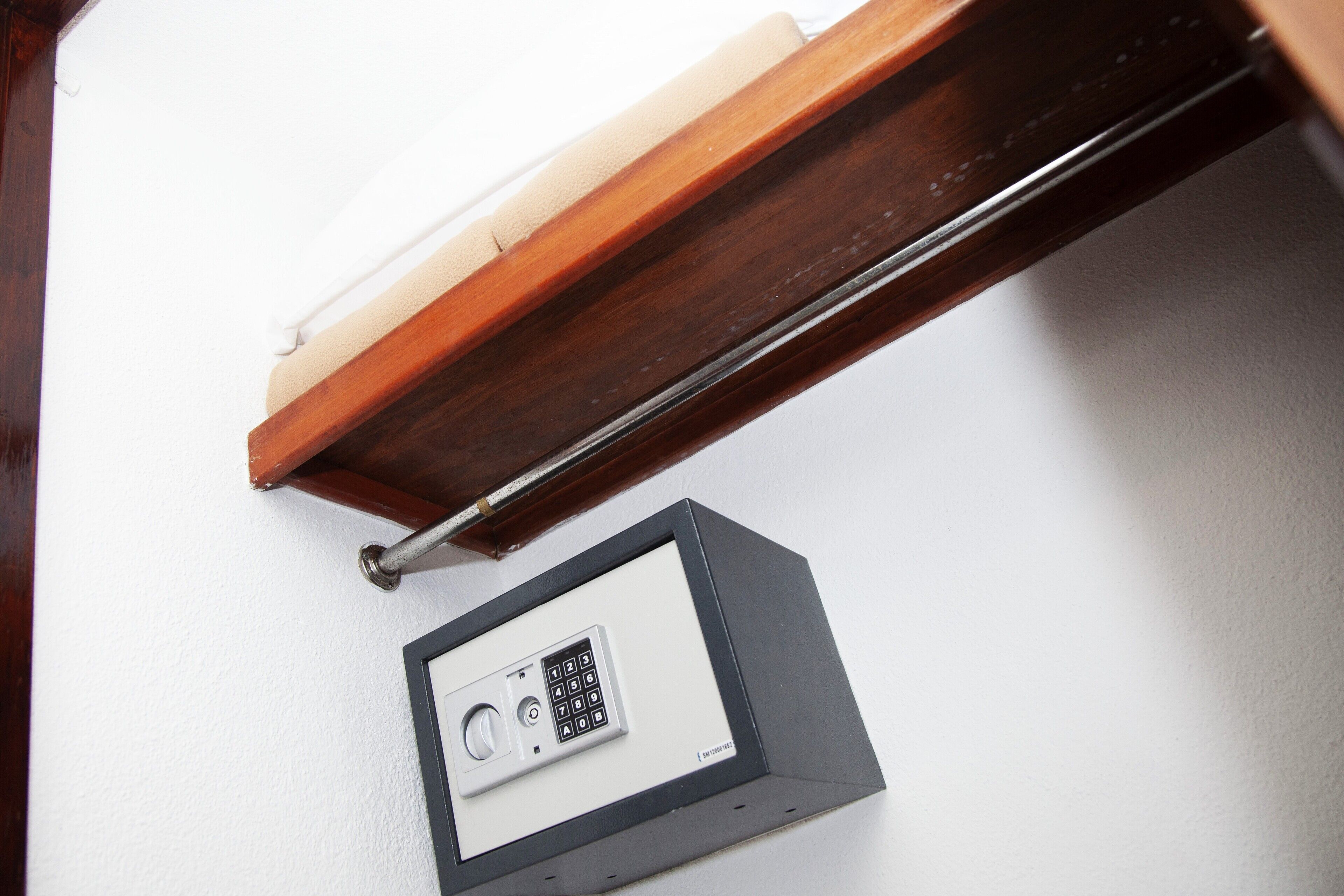 Un panel de control de seguridad en una pared blanca, un marco de puerta de madera y un picaporte metálico.