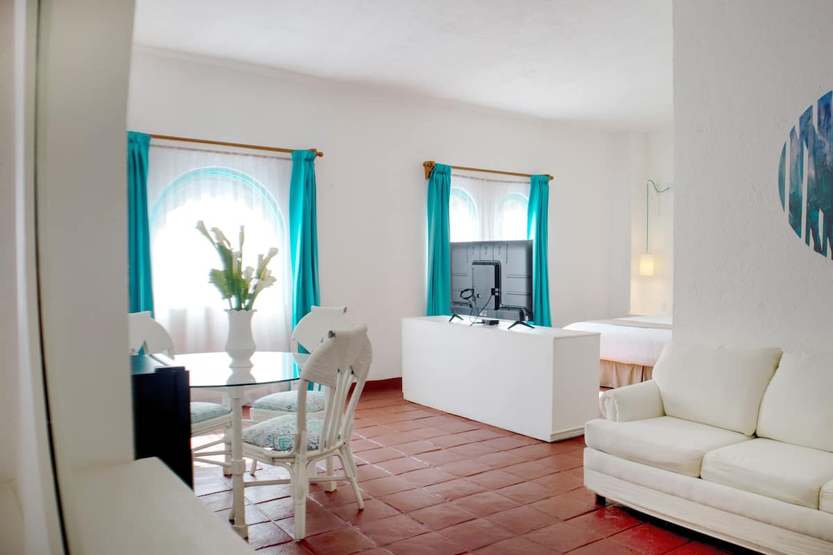 Een moderne woonkamer met een witte bank, een eettafel met stoelen en een tv op een dressoir.