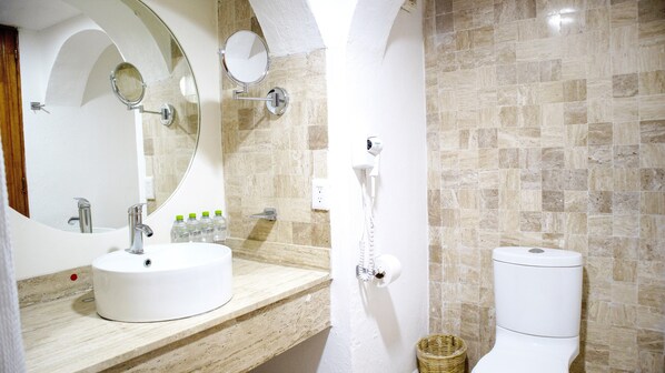 A bathroom with a white sink, two mirrors, a toilet, and a shower area.