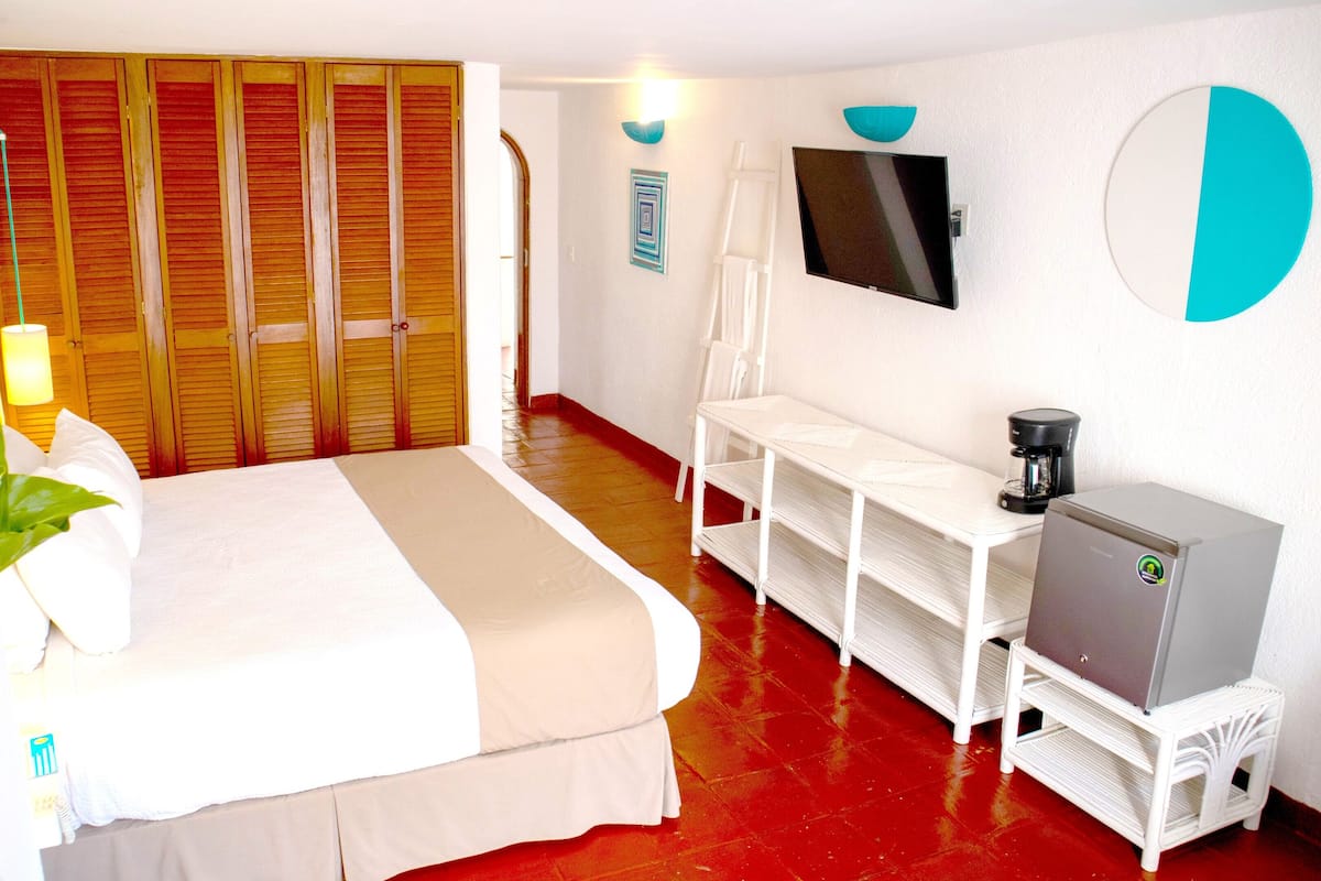 Een hotelkamer met een bed, een bureau, een televisie en een koffiezetapparaat.