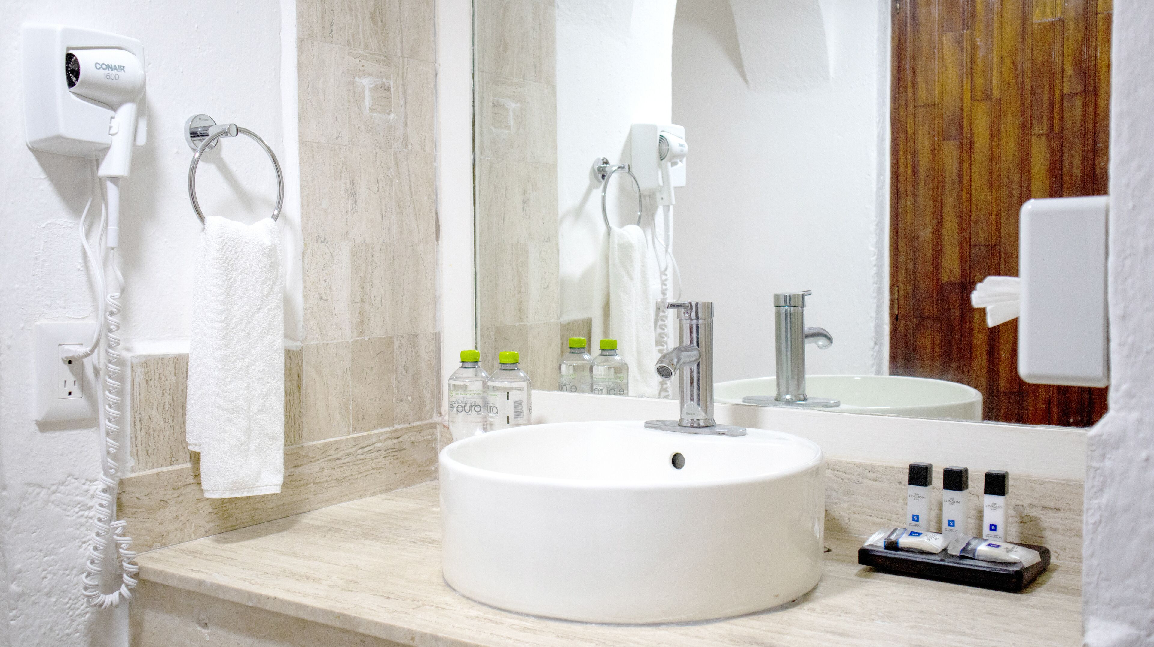 A bathroom with a white sink, a mirror, a towel rack, and a hairdryer.