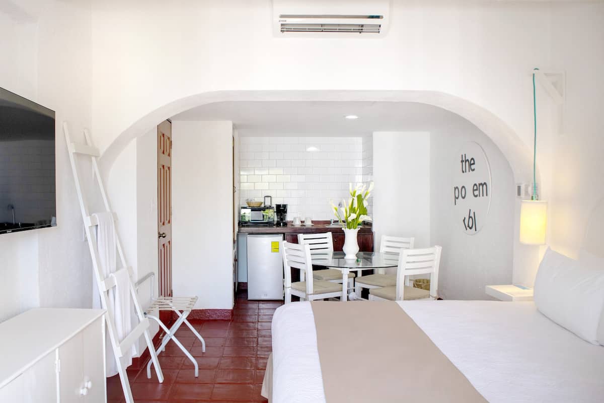 Een hotelkamer met een bed, een bureau, een stoel, een eettafel en een kitchenette.