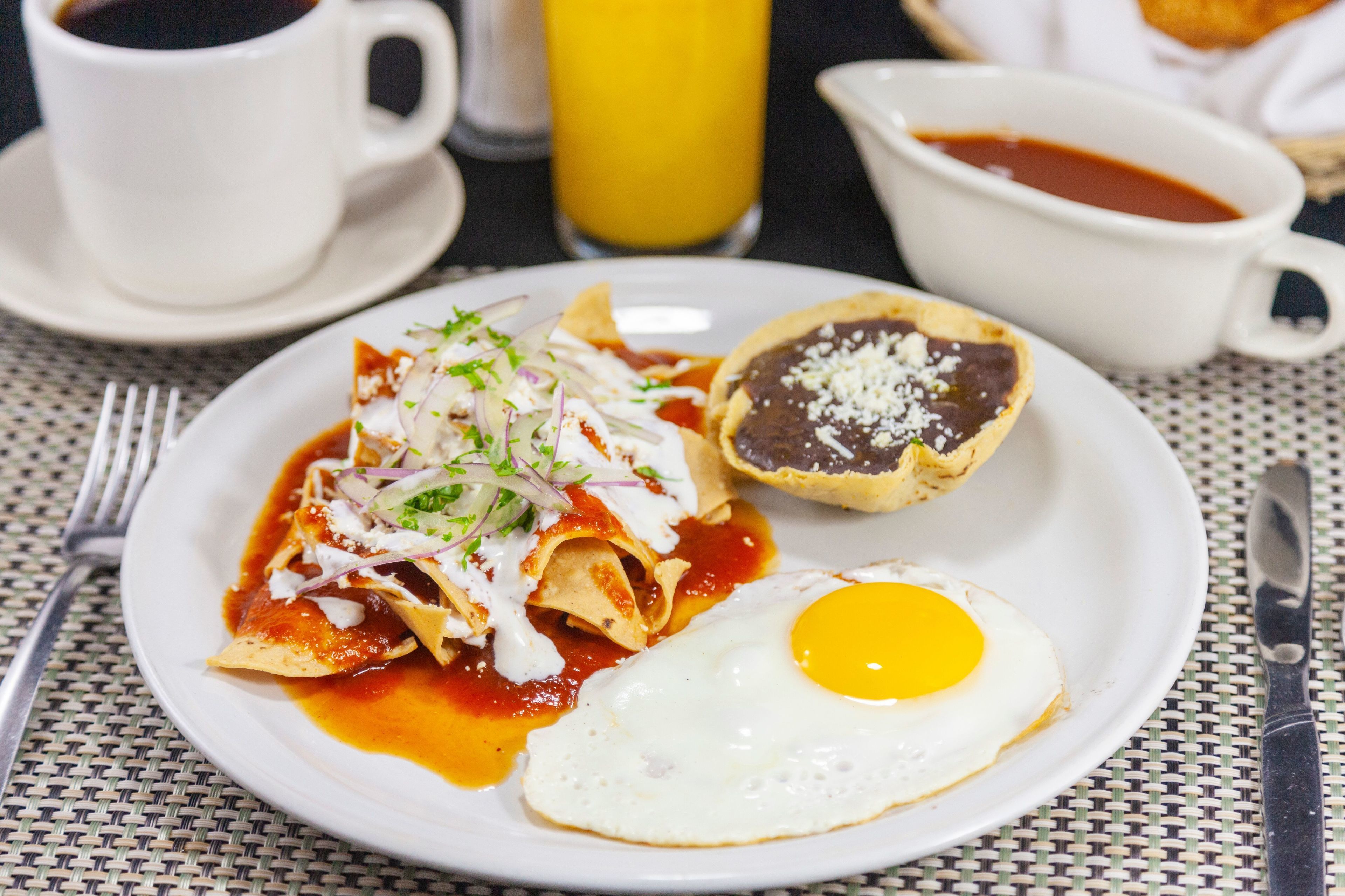 A plate of nachos with a fried egg and a bowl of salsa.