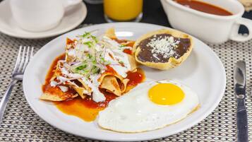 A plate of nachos with a fried egg and a bowl of salsa.