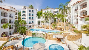 Un resort con varias piscinas, zonas de descanso y un patio con muros de piedra.
