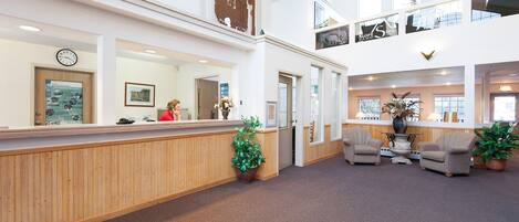 A hotel lobby with a reception desk, seating area, and a staircase leading to an upper level.