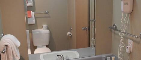 Une salle de bain équipée d’un lavabo, d’un miroir, d’un porte-serviettes et d’un sèche-cheveux.