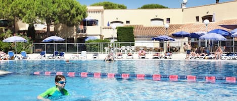 A swimming pool with clear lane dividers, lounge chairs, and umbrellas.
