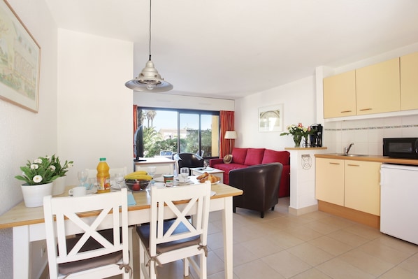 Un espacio habitable compacto con comedor, kitchenette y un sofá rojo.