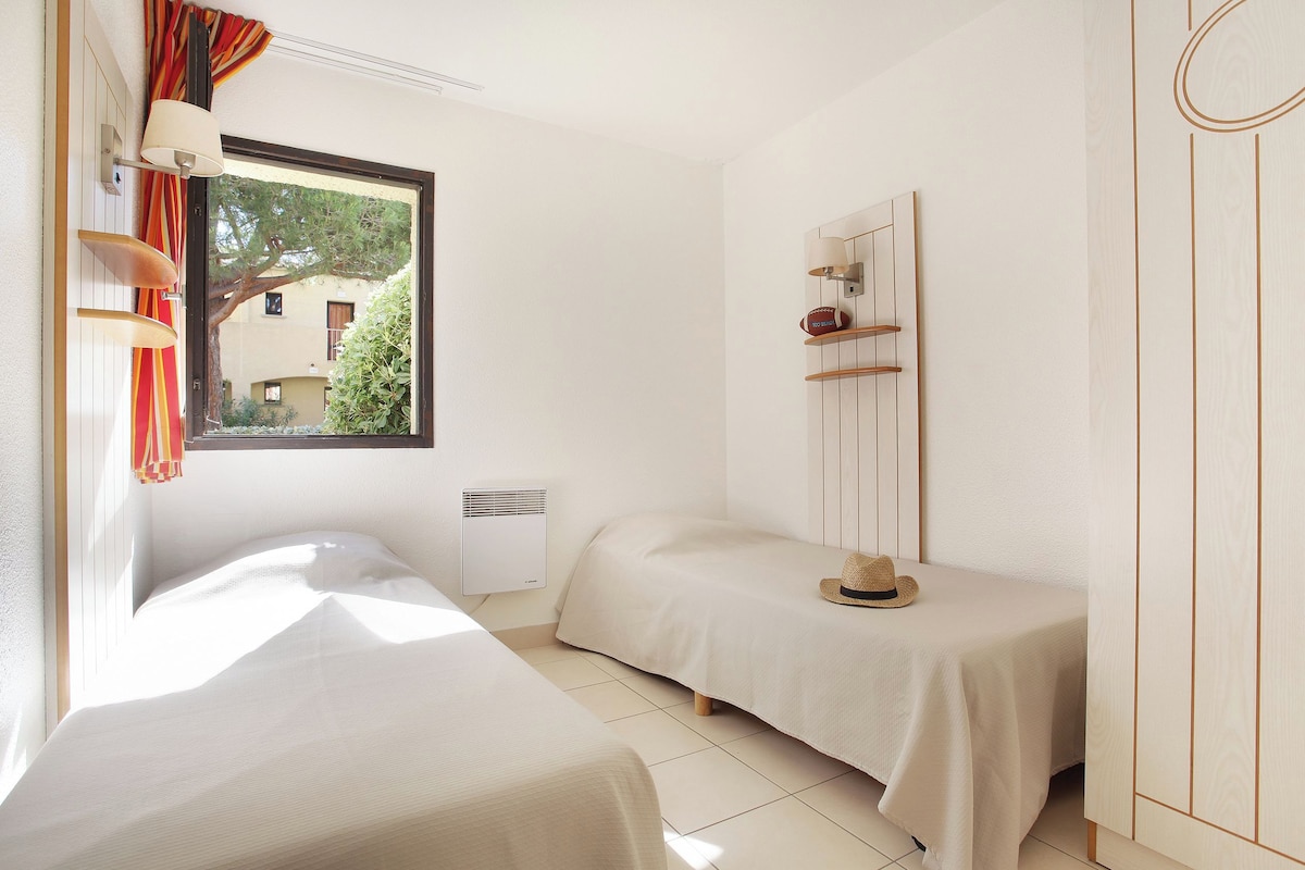 A bedroom with two beds, a window, a mirror, and a wardrobe.