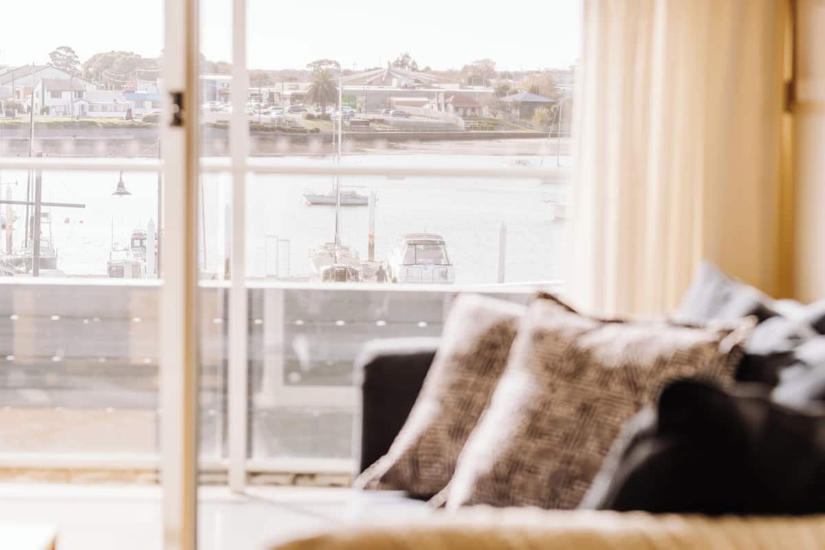 A living room with a view of a marina through a large window.