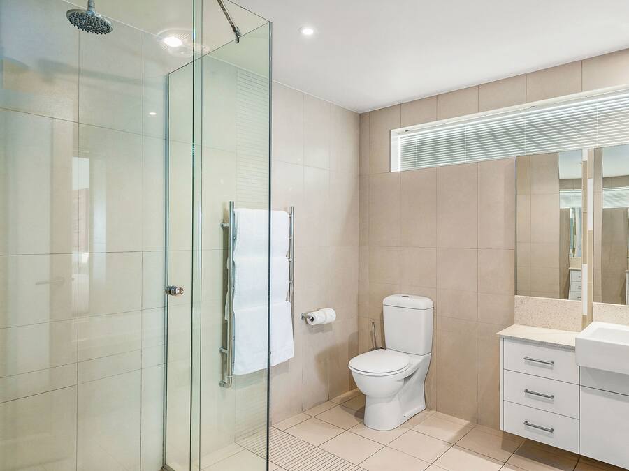 A modern bathroom with a glass shower enclosure, a toilet, and a vanity with a mirror.