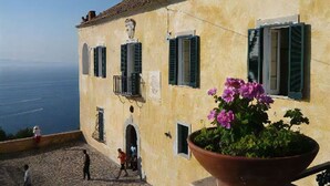 Ein Gebäude mit einer Steintreppe, einem großen Blumentopf und Blick auf das Meer.