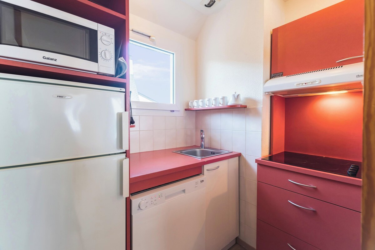 A compact kitchen with a microwave, refrigerator, sink, and dishwasher.