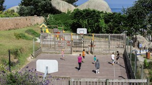 A playground with a basketball hoop, surrounded by a wooden fence and greenery. - Belambra Clubs Trégastel - Le Castel Sainte Anne (Tregastel)
