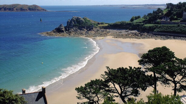 A coastal landscape with a sandy beach, a rocky outcrop, and a lighthouse in the distance. - Belambra Clubs Trégastel - Le Castel Sainte Anne (Tregastel)