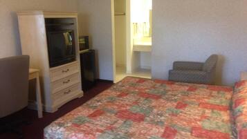 Habitación de hotel con cama, escritorio, silla, cómoda y vestidor.