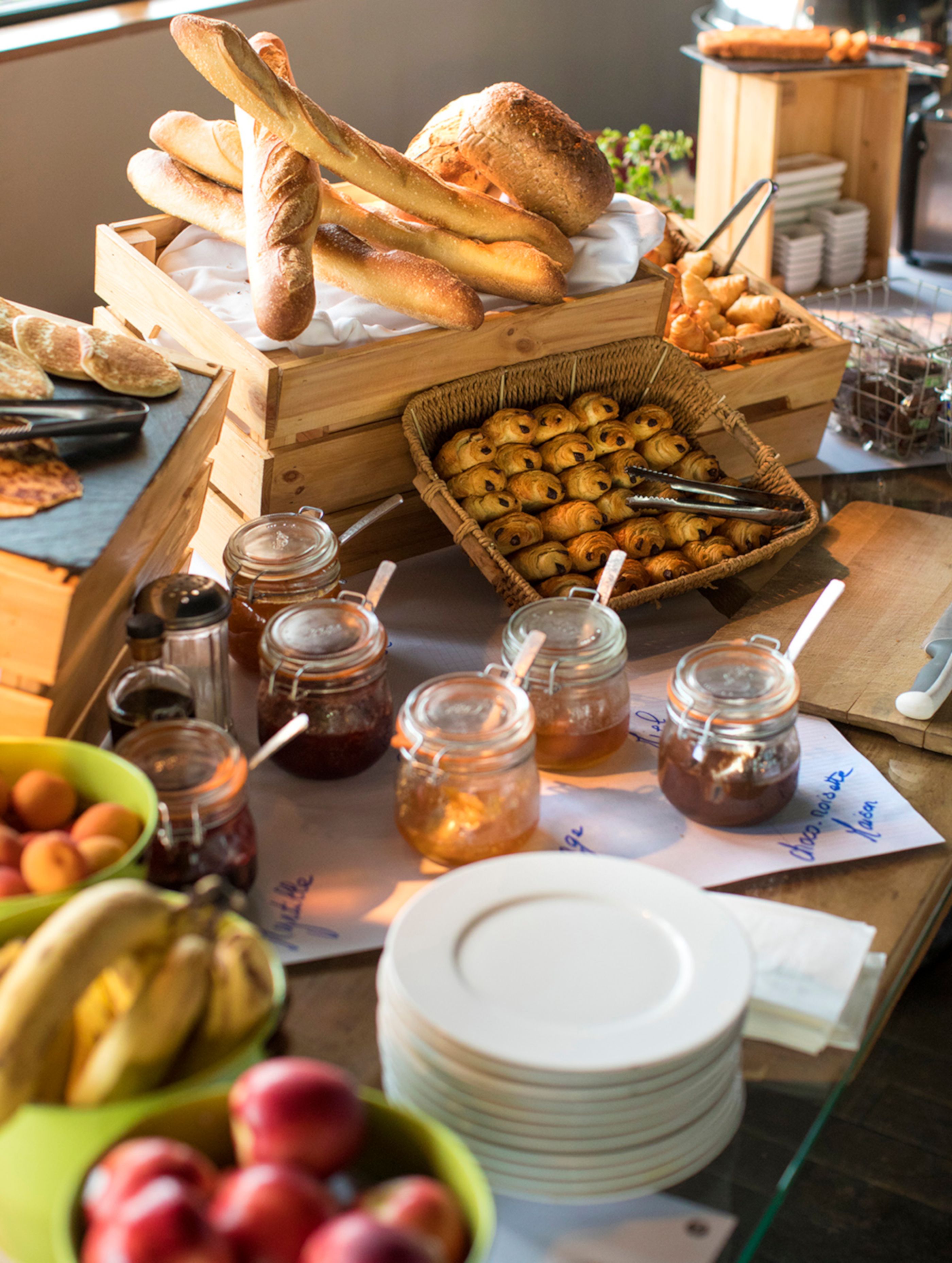 A breakfast buffet with bread, pastries, and fruit.