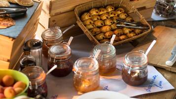 A breakfast buffet with bread, pastries, and fruit.