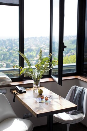 A desk with a vase of flowers, a phone, and a pair of glasses.