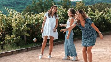 A group of people playing a ball game in an outdoor setting with a vineyard in the background.