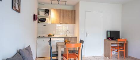 A compact living space with a kitchenette, a dining area, and a seating area with a couch and chairs.