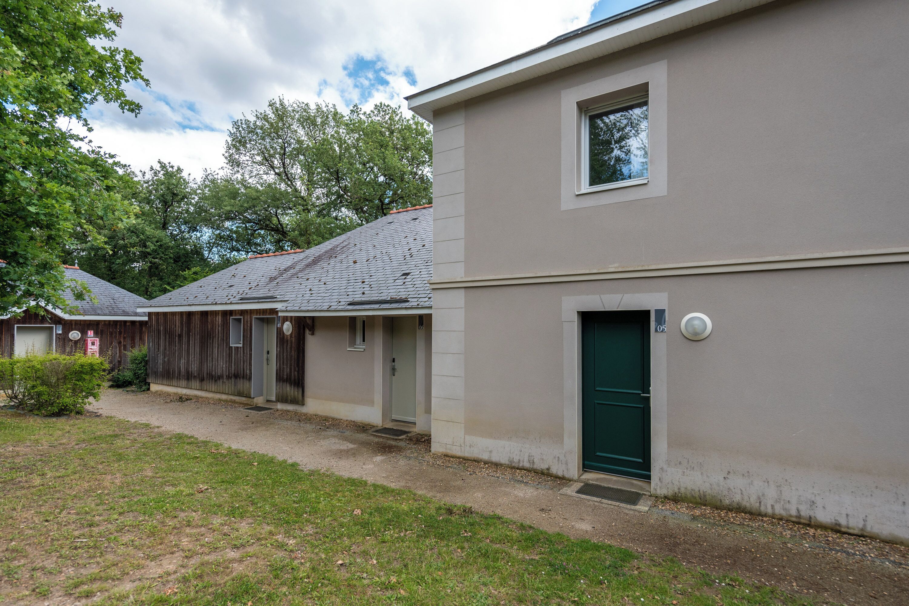 Un bâtiment à deux étages avec une porte verte et une petite fenêtre.