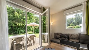 Ein modernes Wohnzimmer mit einer Couch, einem Couchtisch und einer Schiebetür zu einer Terrasse mit Tisch und Stühlen.