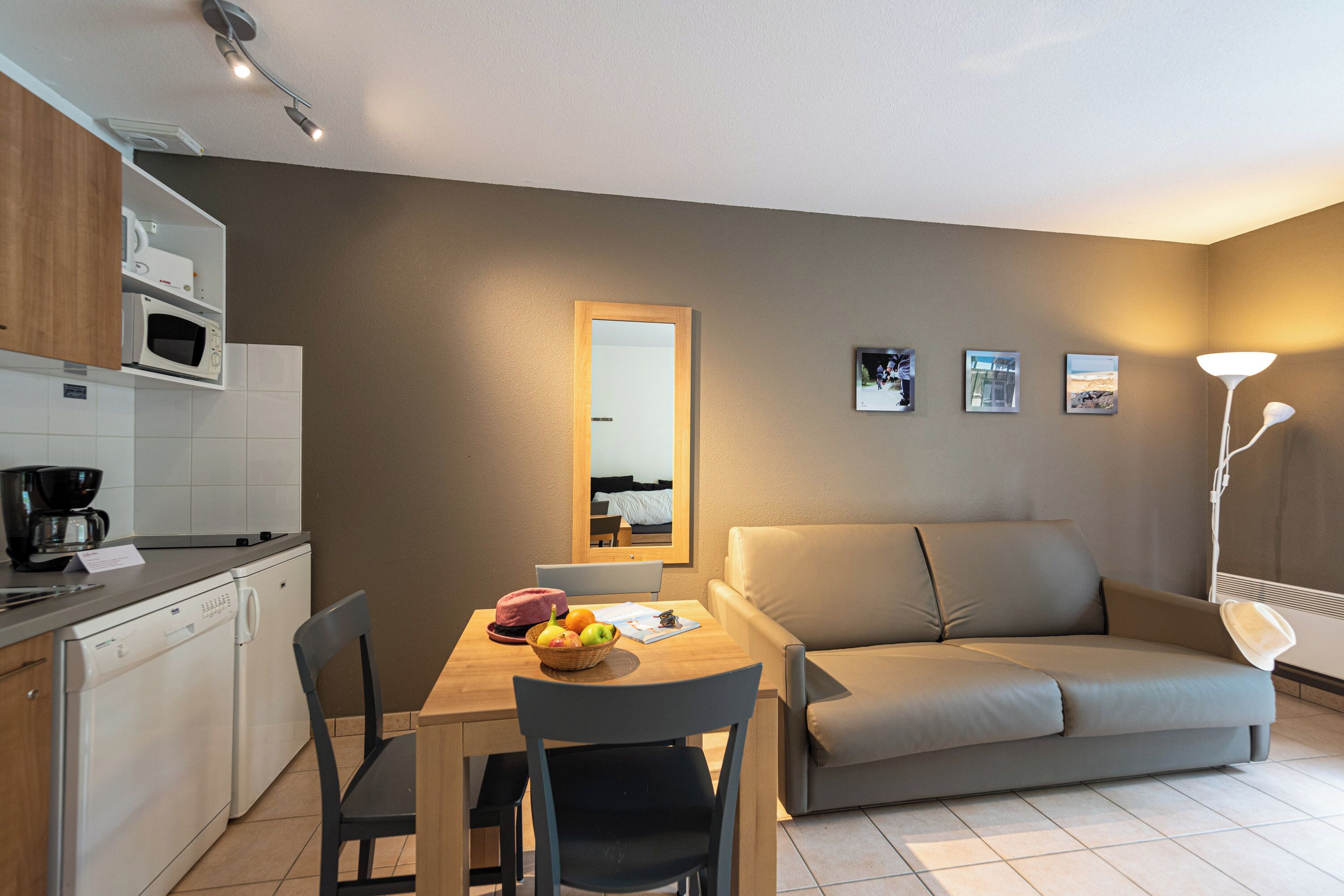 Un espace de vie compact comprenant un coin cuisine, un coin repas et un coin salon.