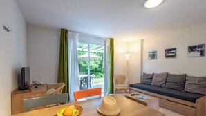 Ein modernes Wohnzimmer mit einer Couch, einem Esstisch und Blick ins Freie.