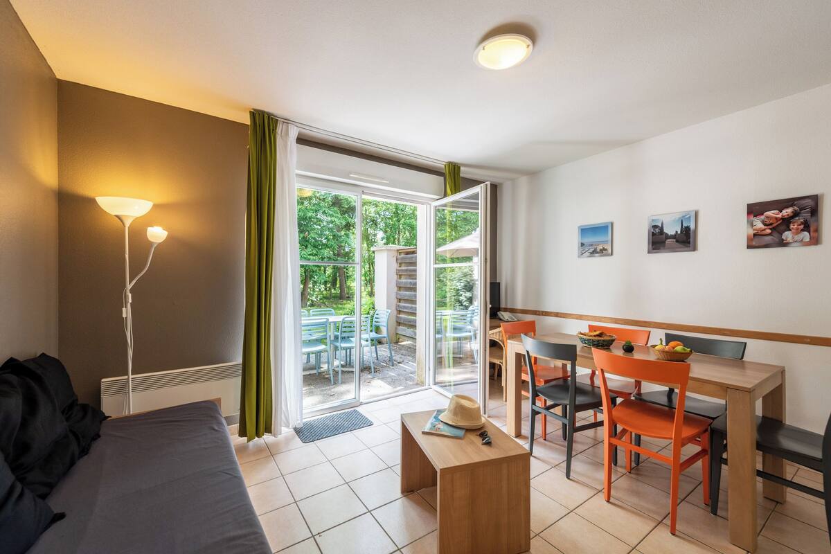 Una habitación moderna con cama, una mesa y sillas, zona de comedor y vistas al exterior.