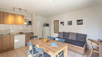 Un espacio habitable compacto con kitchenette, comedor y sofá cama.