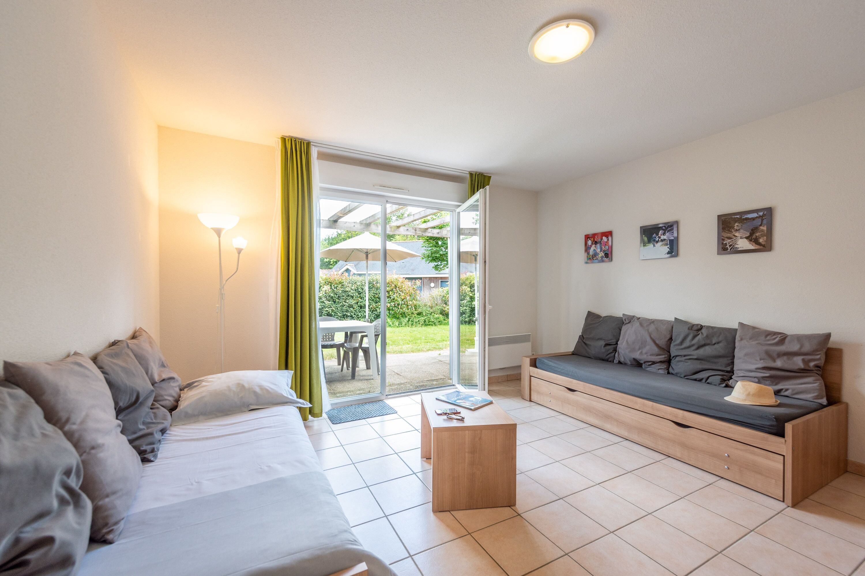 Ein modernes Zimmer mit einer Couch, einem Bett, einem Holztisch und einer Glastür zum Außenbereich.