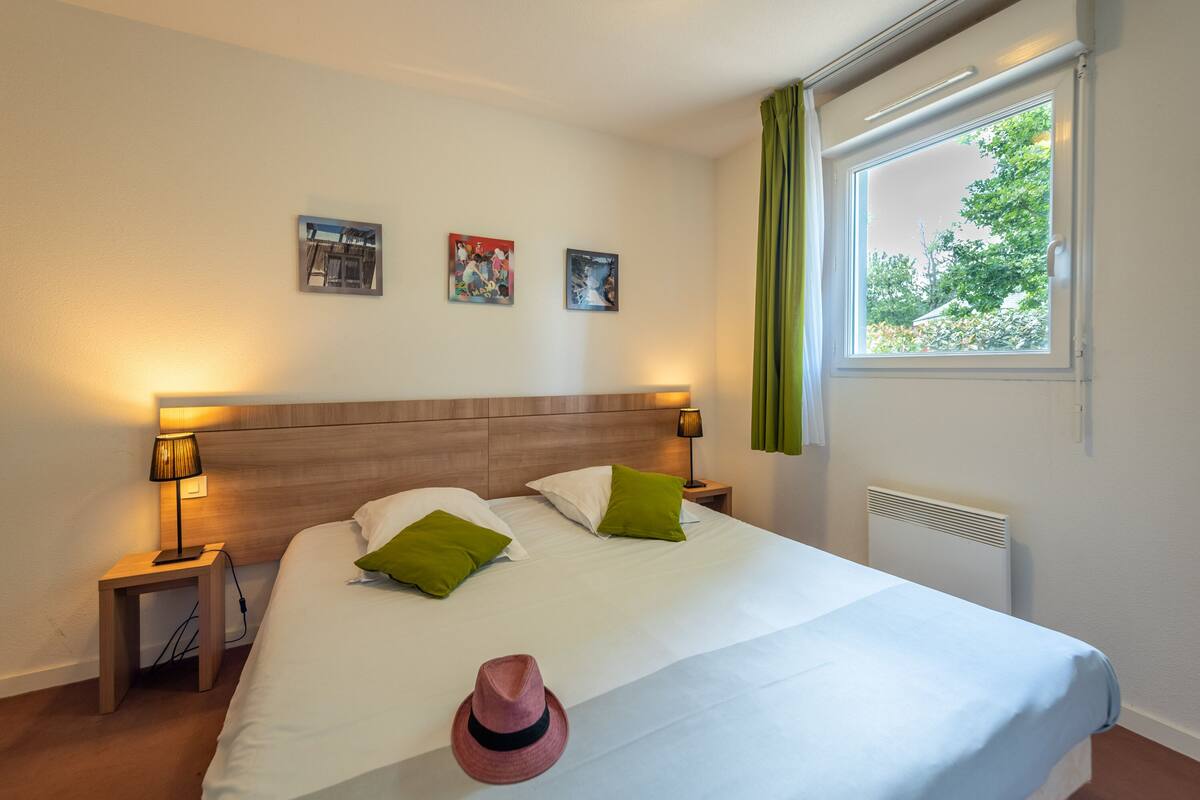 Habitación de hotel con una cama grande, dos mesitas de noche, una ventana con cortinas y decoración en la pared.