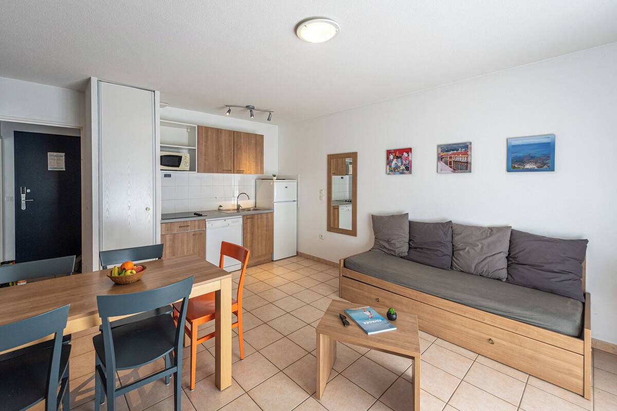 Un espacio habitable compacto con kitchenette, comedor y sofá.