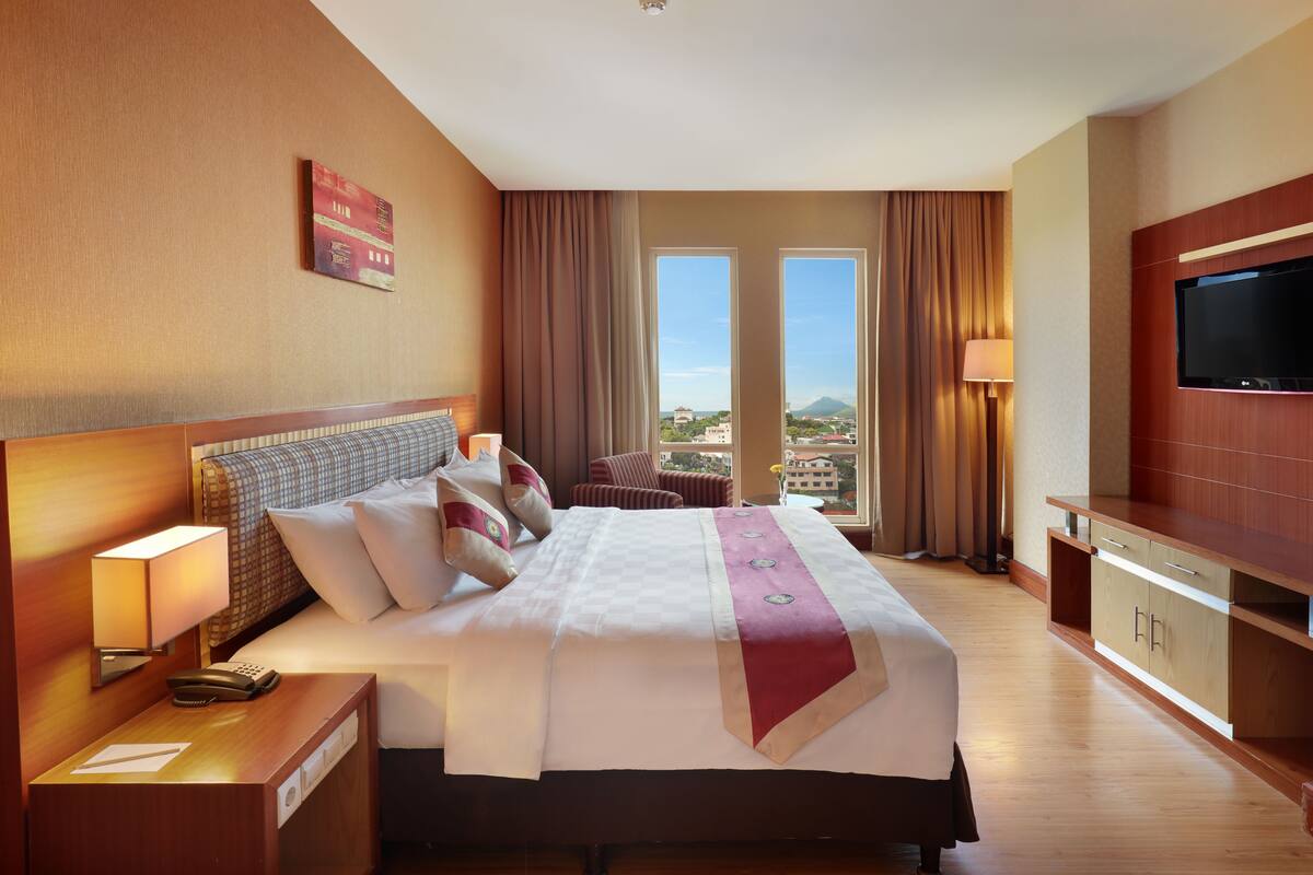 Una habitación de hotel con una cama grande, televisión, escritorio y vistas a la ciudad.