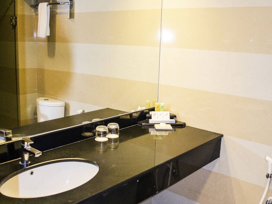 A modern bathroom with a large mirror, a sink, and a shower.