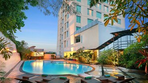 A swimming pool with lounge chairs and a building with multiple windows.