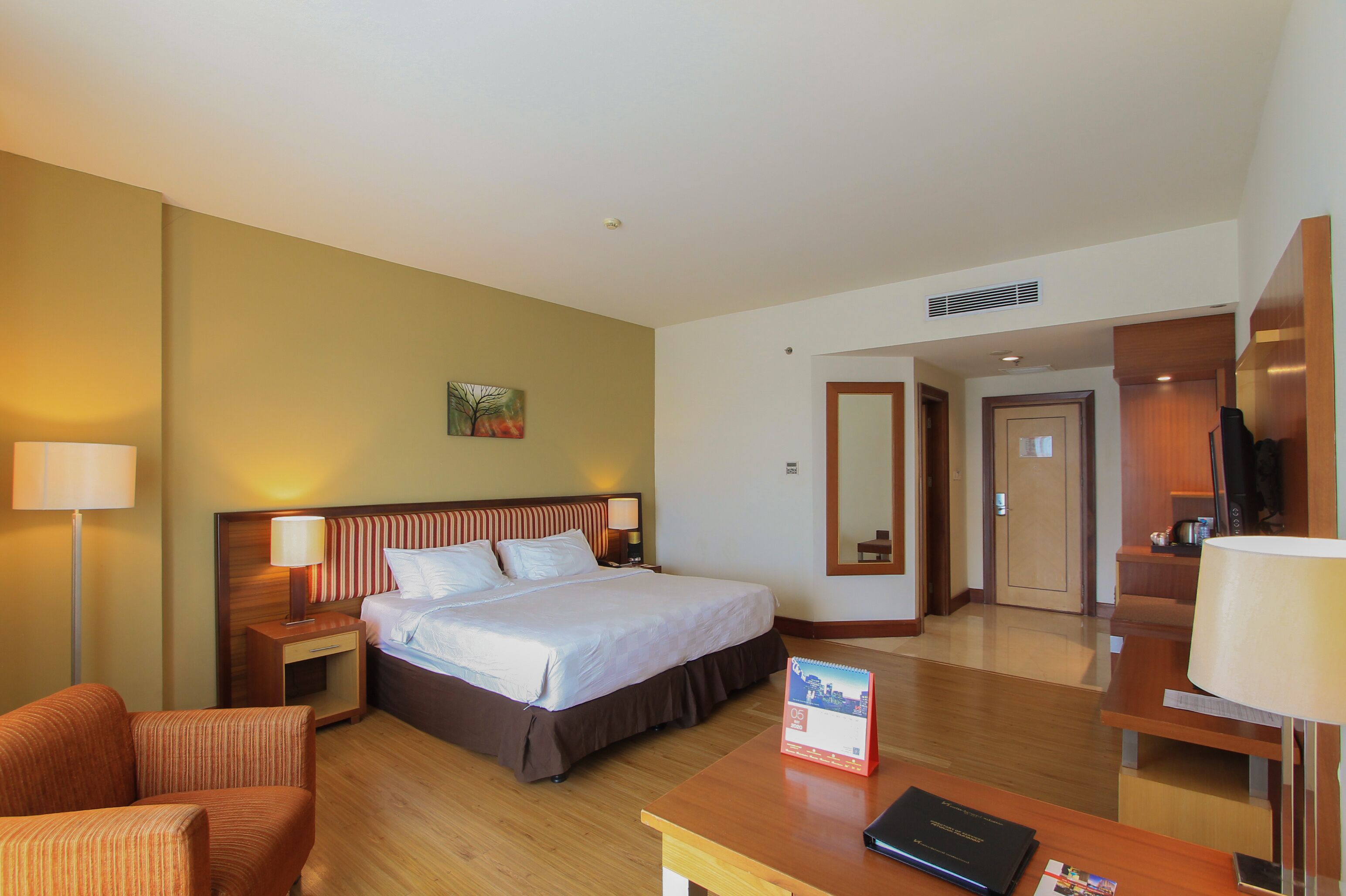 A hotel room with a large bed, a desk, a chair, and a TV.