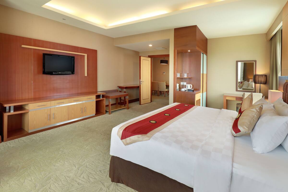 Habitación de hotel con una cama grande, televisión montada en la pared, escritorio y una silla.