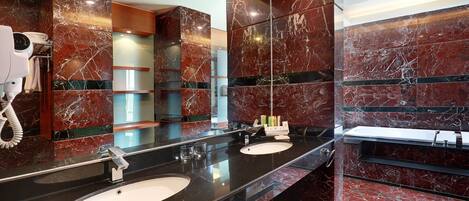 Un baño moderno con dos lavamanos, paredes de mármol y un espejo grande.